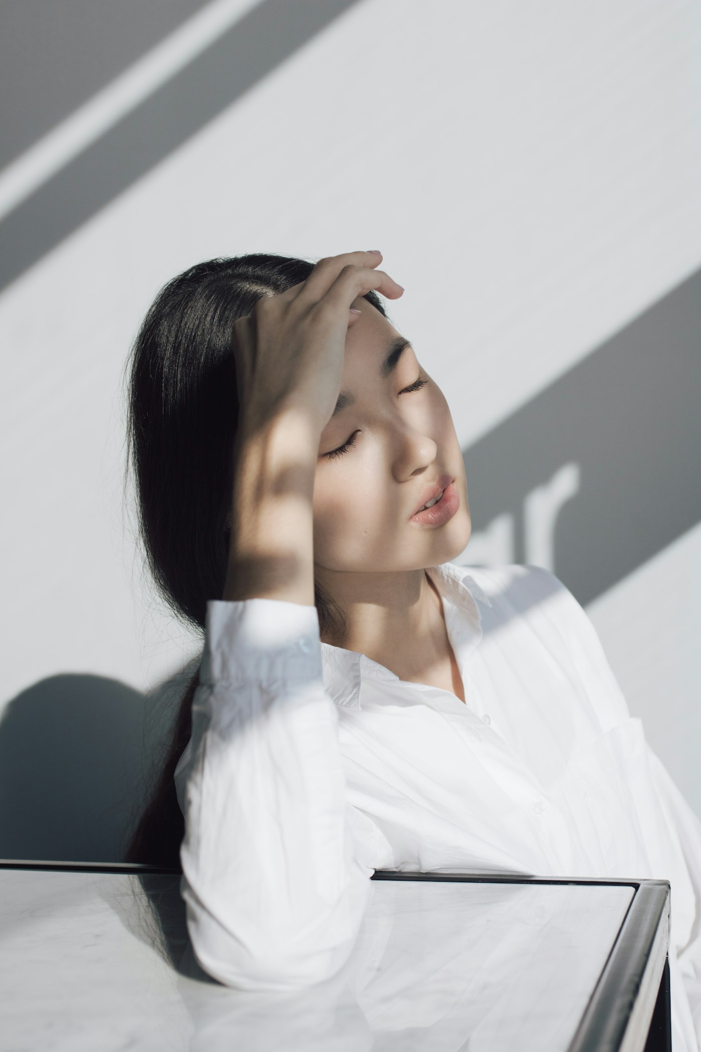 Model in a white shirt resting in soft daylight